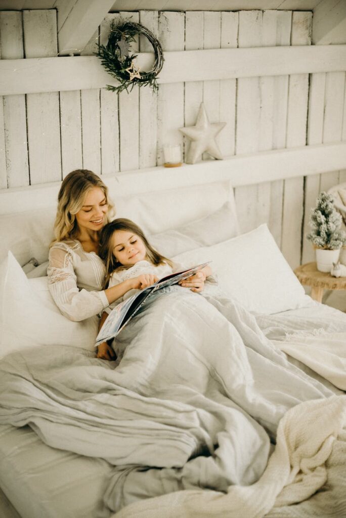A mother and daughter enjoy a relaxing moment reading a book in a beautifully decorated bedroom.